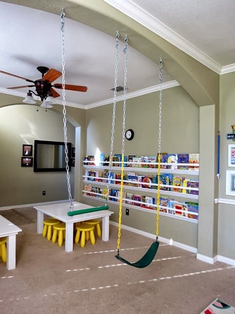 a child's playroom with swings, tables and toys on the carpeted floor