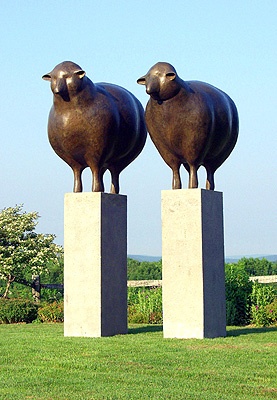 two statues of sheep standing on top of cement blocks