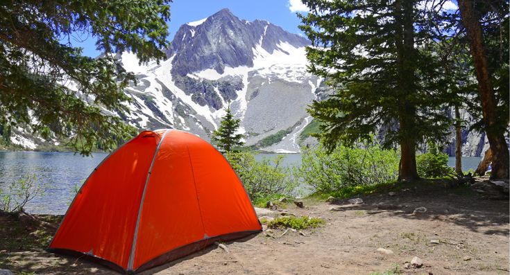 an orange tent sitting on the side of a lake