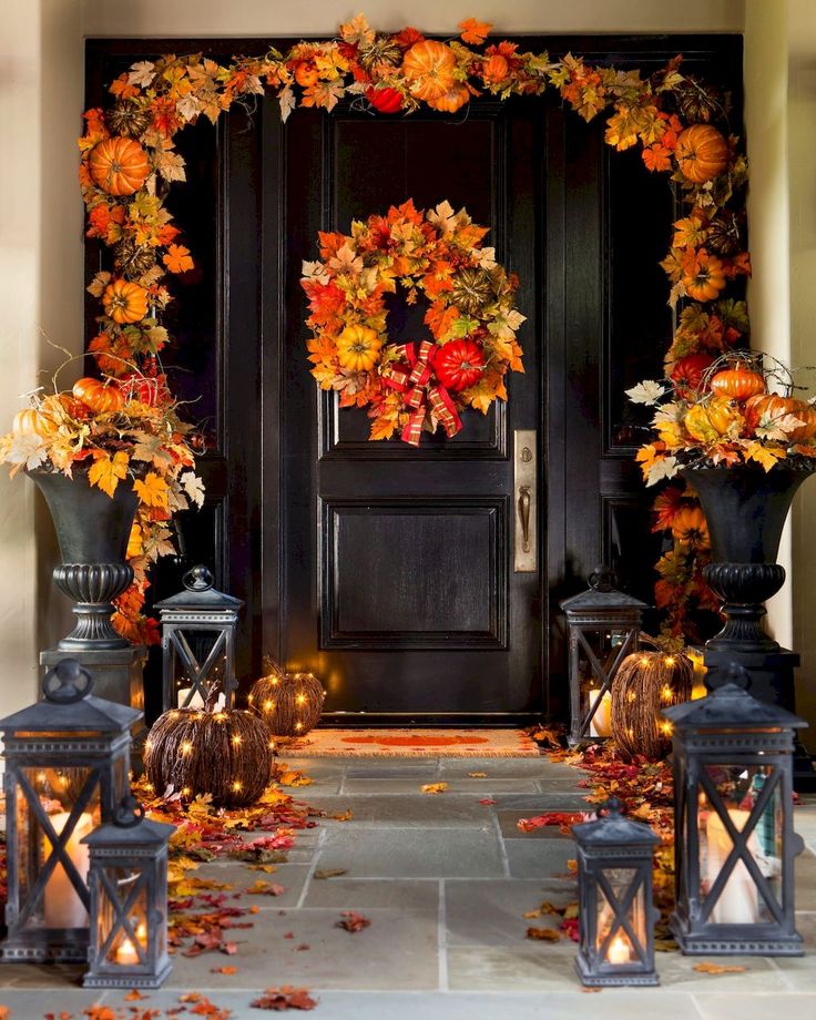 a front door decorated with fall leaves and candles