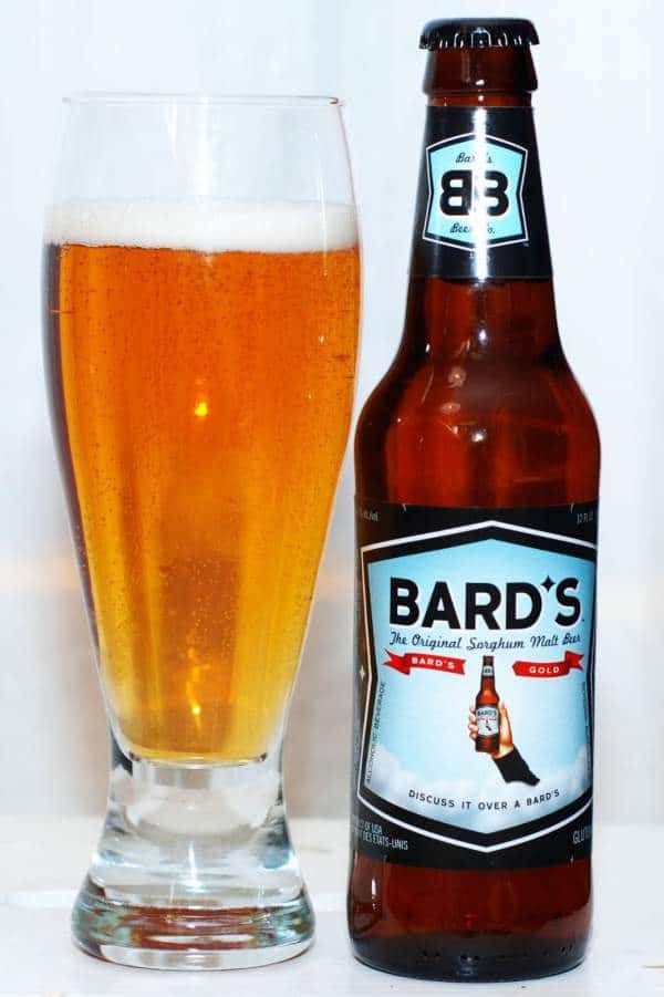 a glass full of beer next to a bottle with the word bard's on it