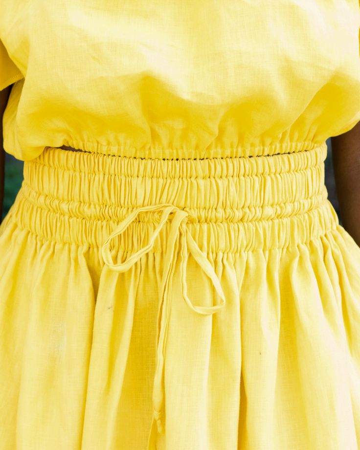 a woman in a yellow dress with her hands on her hips