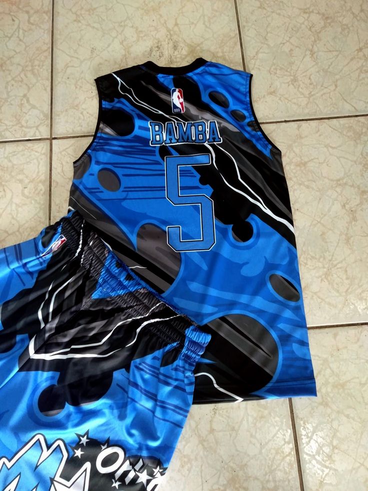 two basketball uniforms sitting on the floor next to each other, one blue and one black