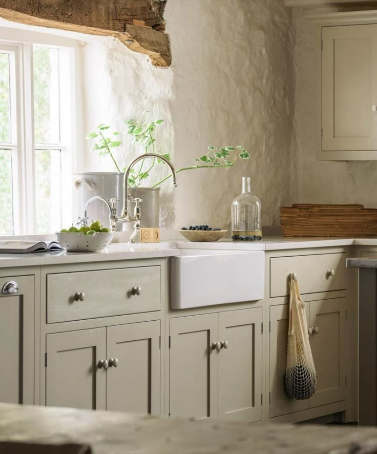 a kitchen filled with lots of white cabinets and counter top space next to a window