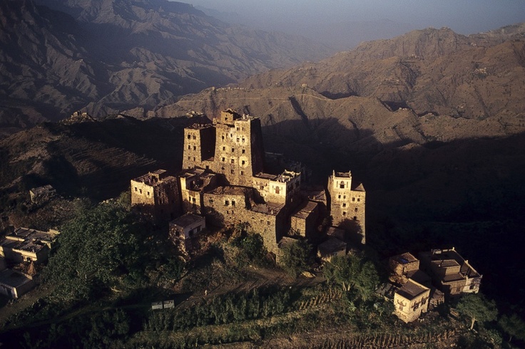 an old castle on top of a mountain in the middle of nowhere, with mountains in the background