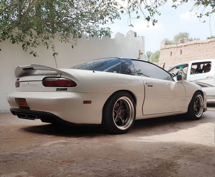 a white sports car parked next to two other cars