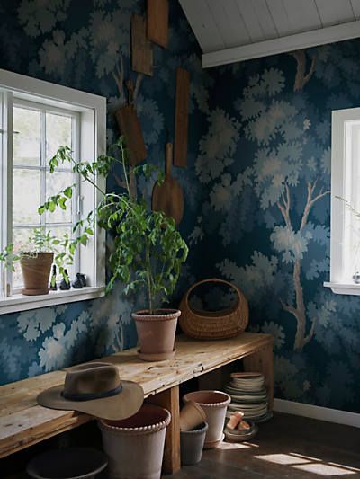 a room with blue and white wallpaper, potted plants and wooden bench in front of the window