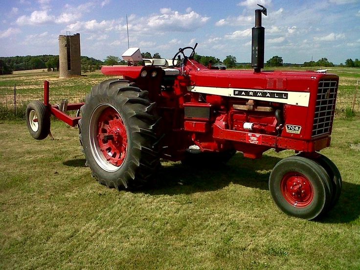 a large red tractor parked on top of a lush green field