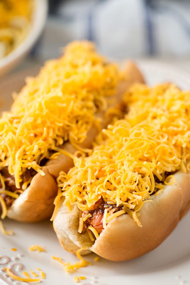 two hot dogs covered in cheese on a plate