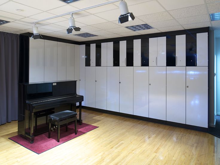 an empty room with black and white cabinets, a piano, and a pink rug