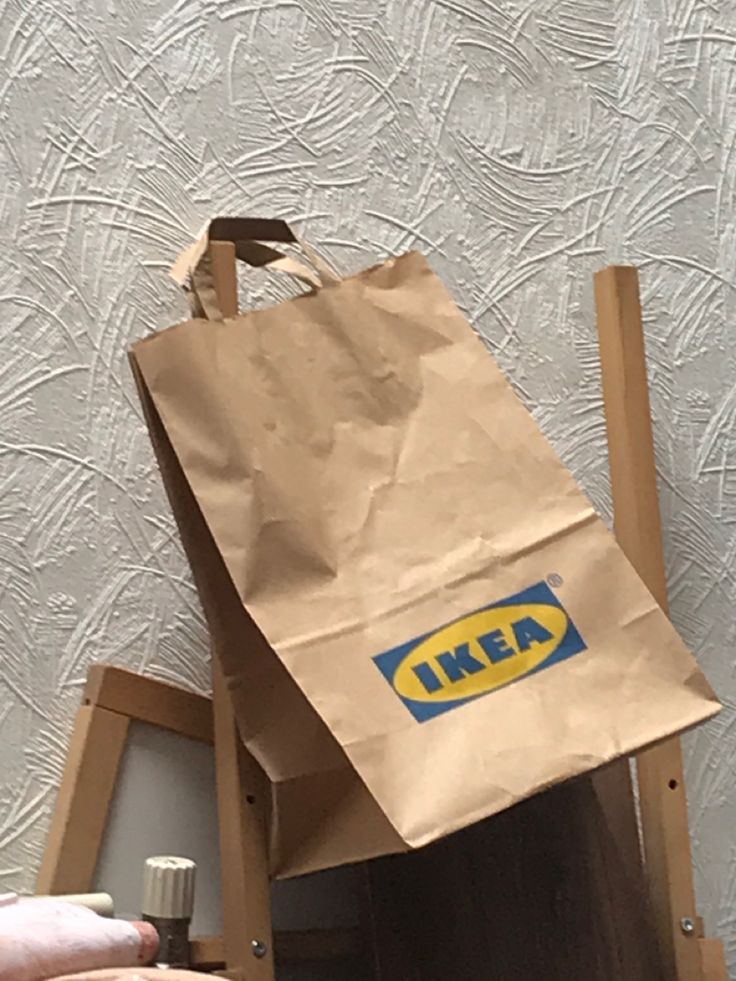 a brown paper bag with the ikea logo on it is being held up by someone's hand