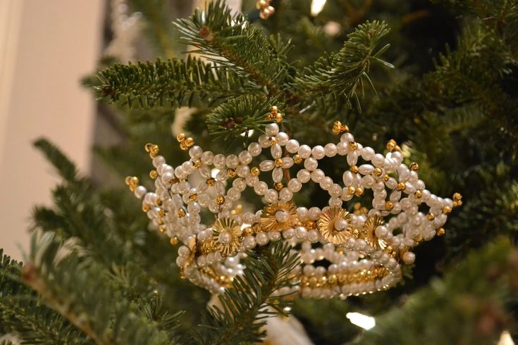 a close up of a christmas tree with beads on it's branches and lights in the background