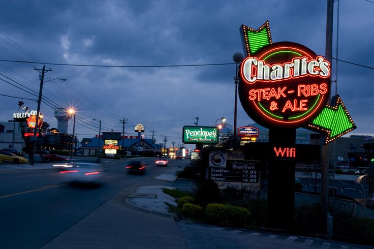 a neon sign that says charlie's steak ribs and ale on the side of a road