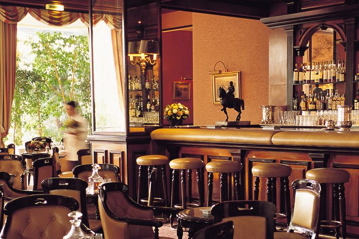 a bar with lots of chairs and barstools in front of a large window