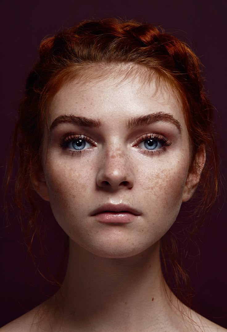 a woman with freckled hair and blue eyes looks at the camera while posing for a portrait