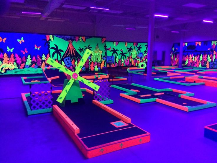 an indoor trampoline park with neon colored walls and purple lighting on the ceiling