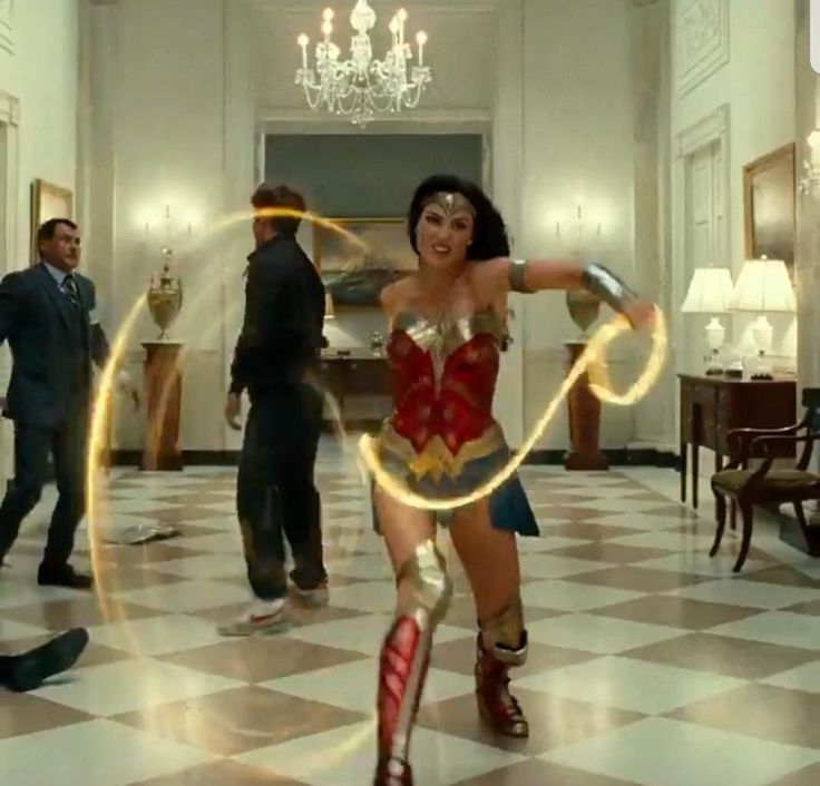 a woman in a costume is dancing with two men and a chandelier behind her