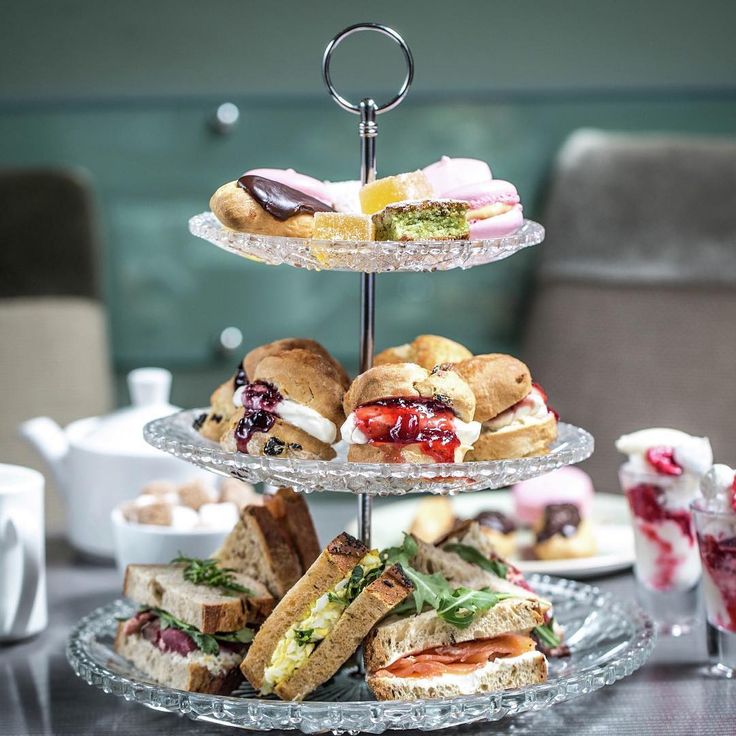 three tiered trays with sandwiches and pastries on them sitting on a table