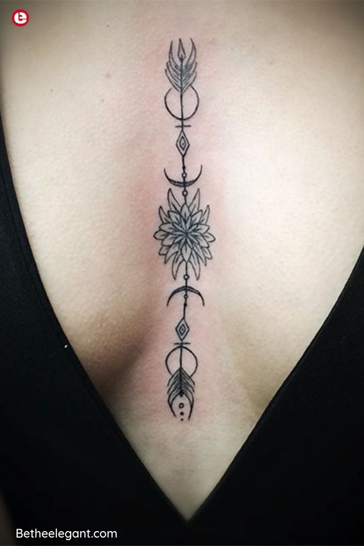 the back of a woman's neck with an arrow and flower tattoo on it