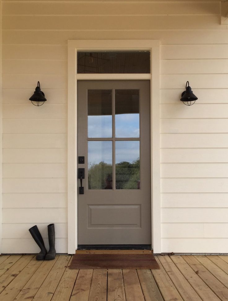 a gray front door with two black boots on the porch