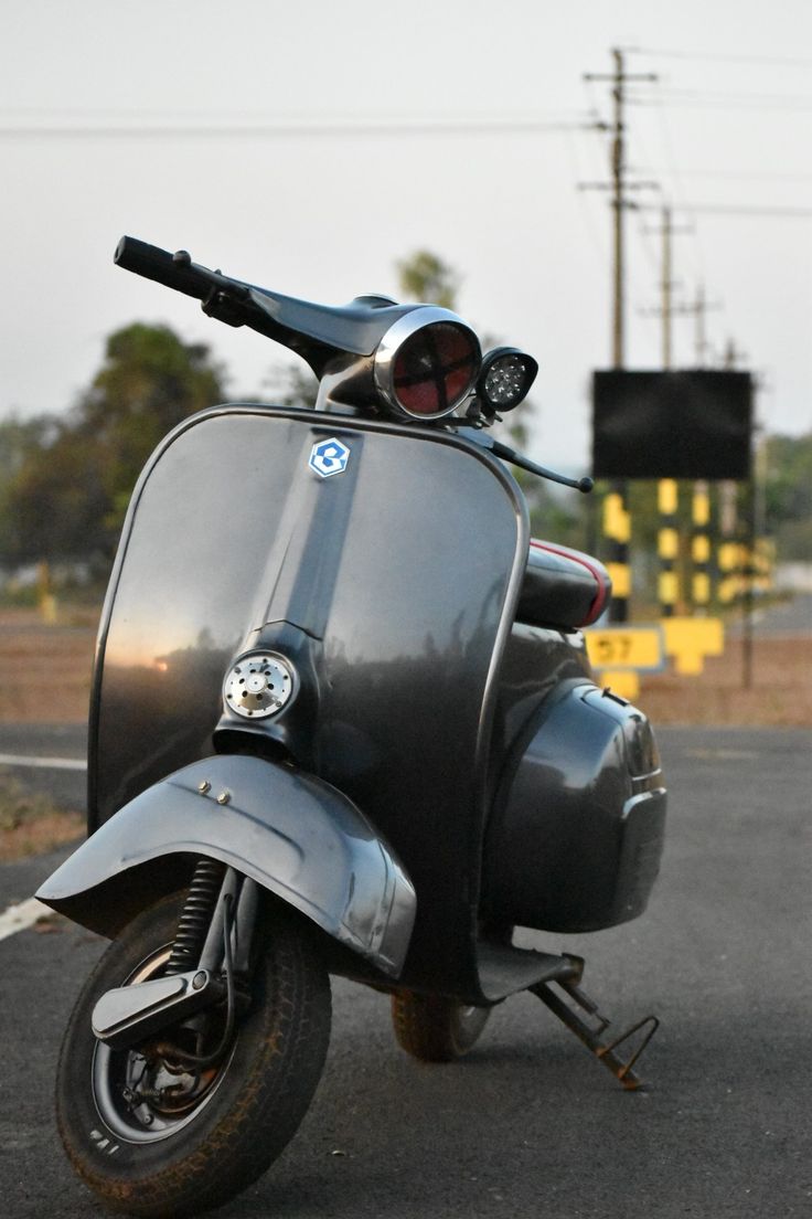 a motor scooter is parked on the side of the road with its lights on