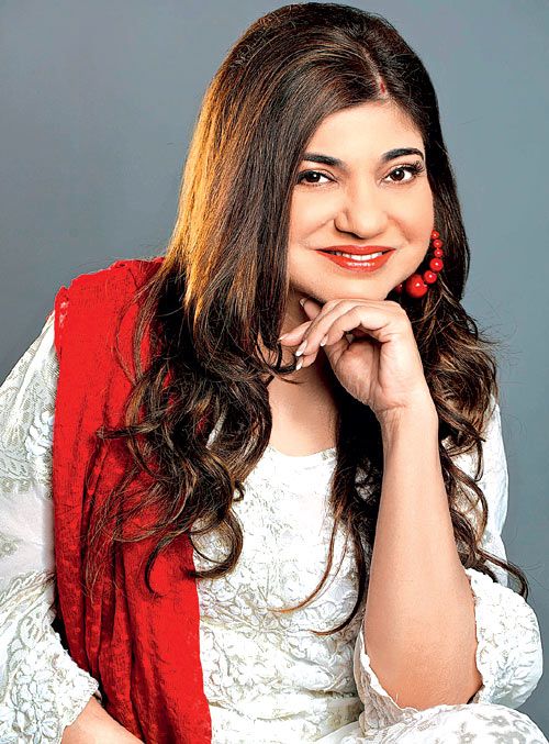 a woman with long hair wearing a white dress and red shawl smiling at the camera