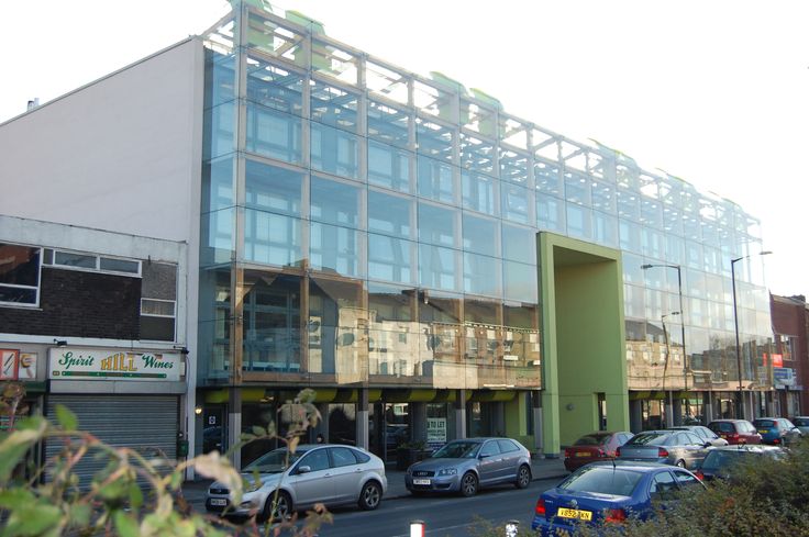 cars are parked in front of a building that is being constructed into a glass and steel structure