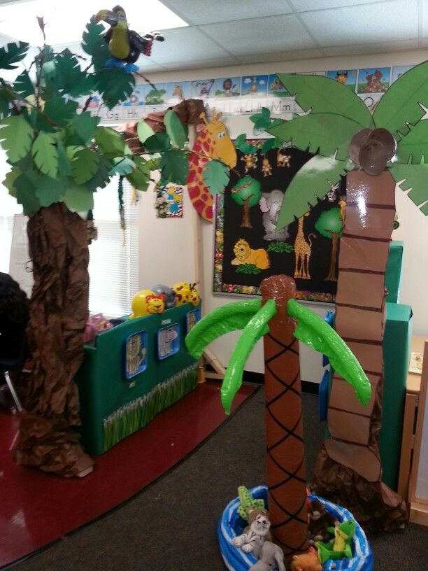 an office decorated with paper palm trees and jungle animals on the desks for kids to play in