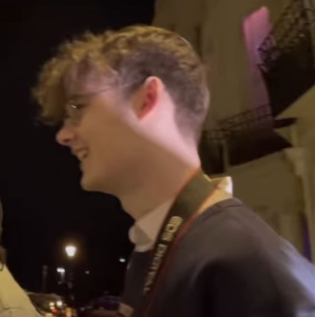 two people standing next to each other in front of a building with lights on it