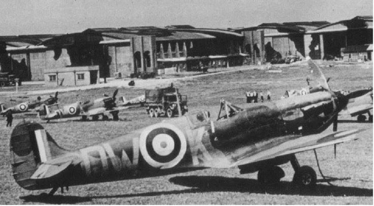 an old black and white photo of airplanes parked in front of some buildings on the grass