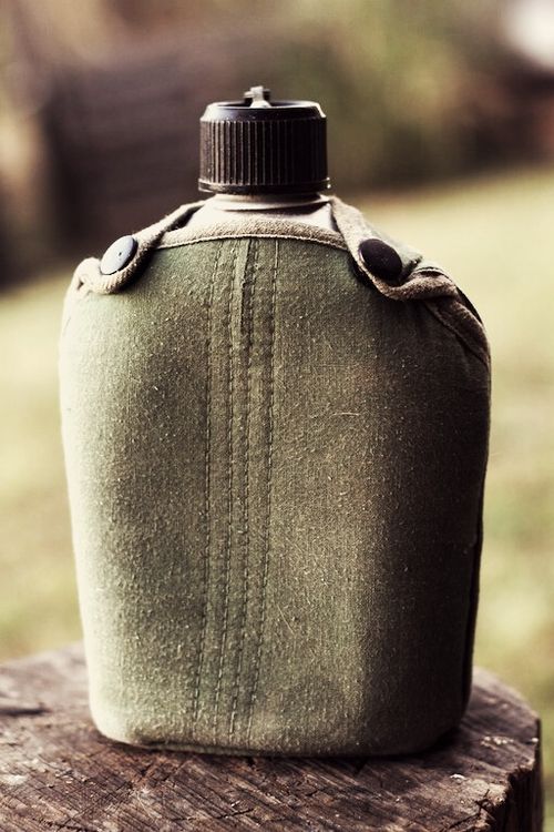 a green flask bottle sitting on top of a wooden table