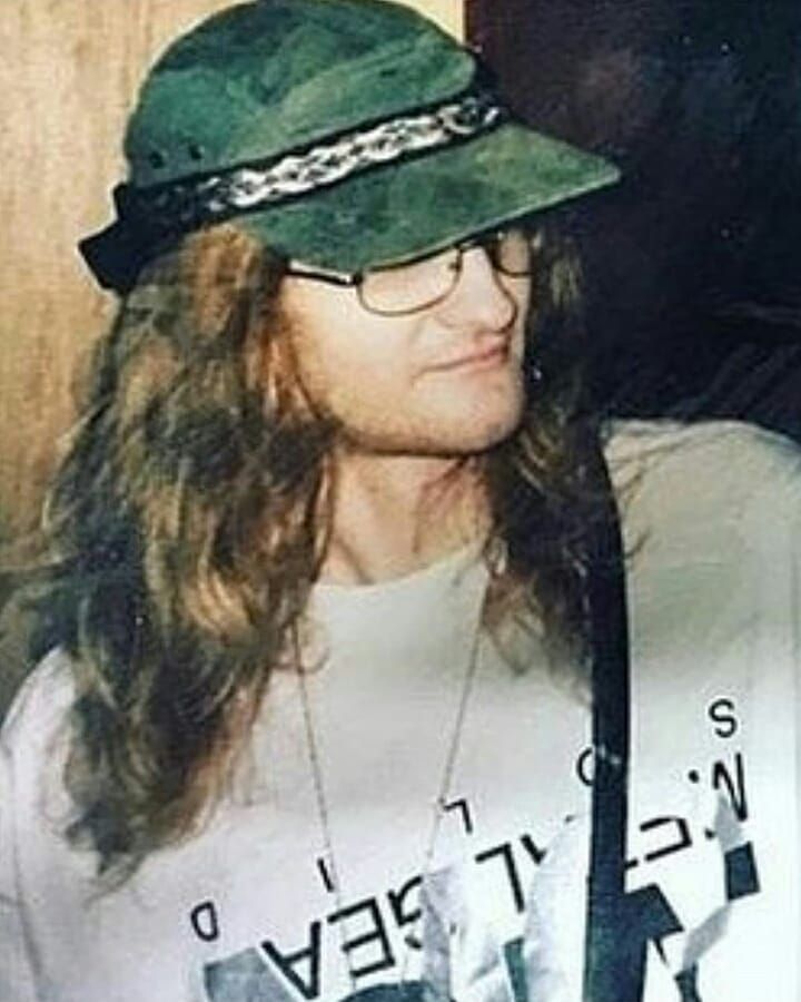 a man with long hair wearing a green hat