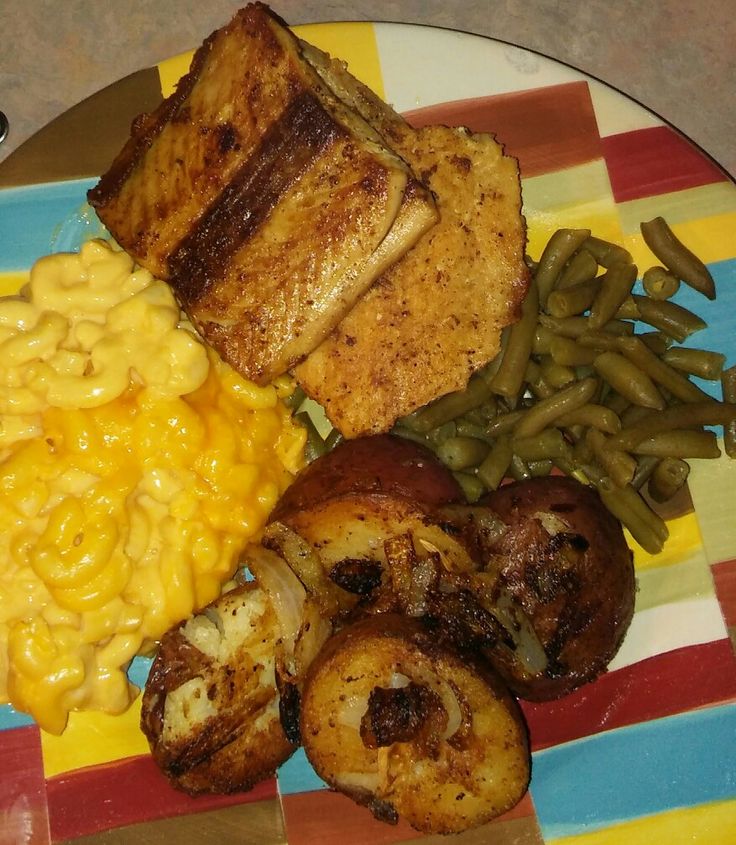 a plate with meat, macaroni and cheese, green beans, and potatoes