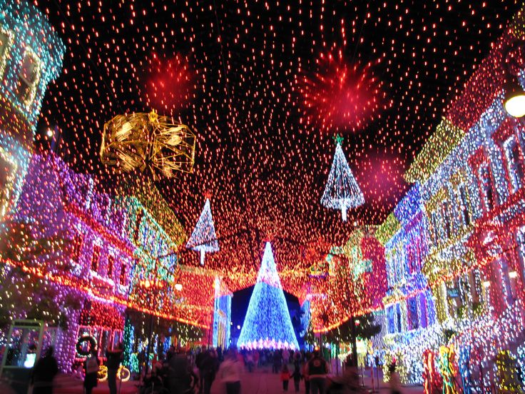 people are walking through the streets covered in christmas lights