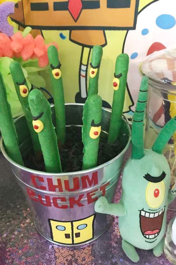 some plants are in a bucket with stuffed animals next to them and other decorations on the table