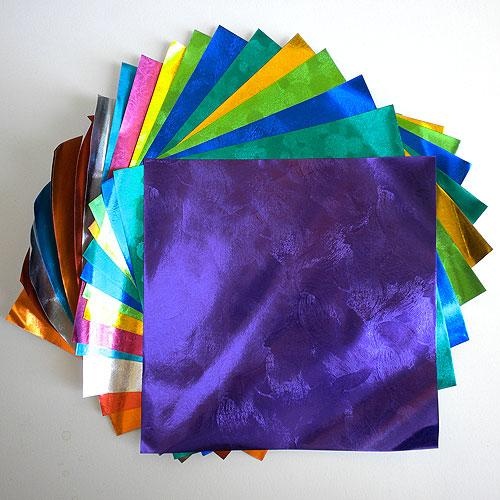 there are many different colors of paper on the table and one has a purple bag