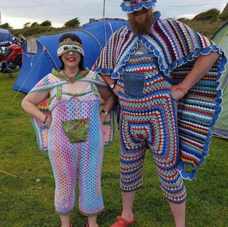 two people dressed in crocheted clothing standing next to each other on grass with tents behind them