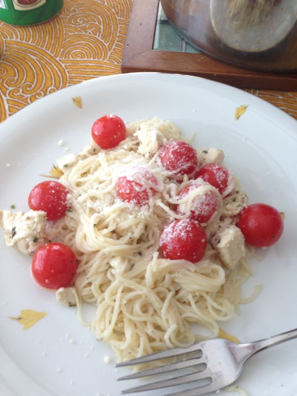 a white plate topped with pasta covered in sauce and cherry tomatoes next to a fork