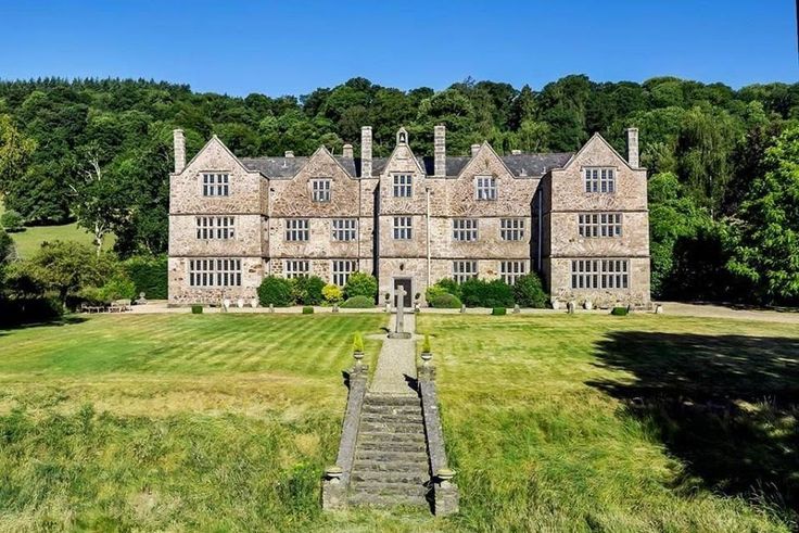 an aerial view of a large stone building in the middle of a lush green field