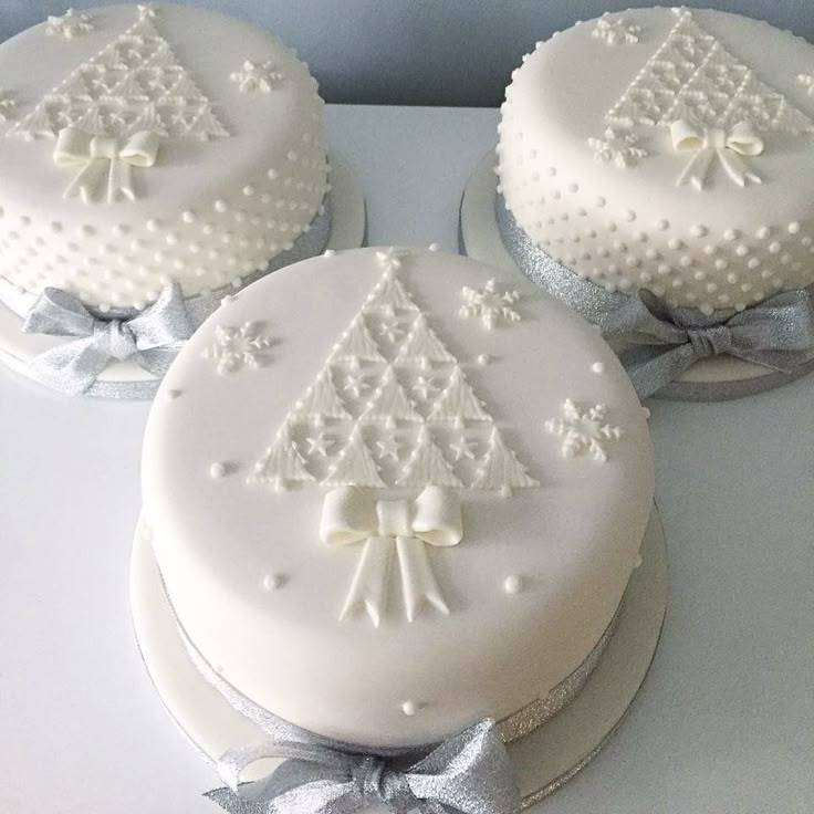 three white cakes decorated with bows and snowflakes