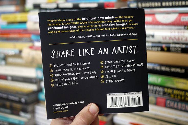 a person holding up a book in front of a pile of books