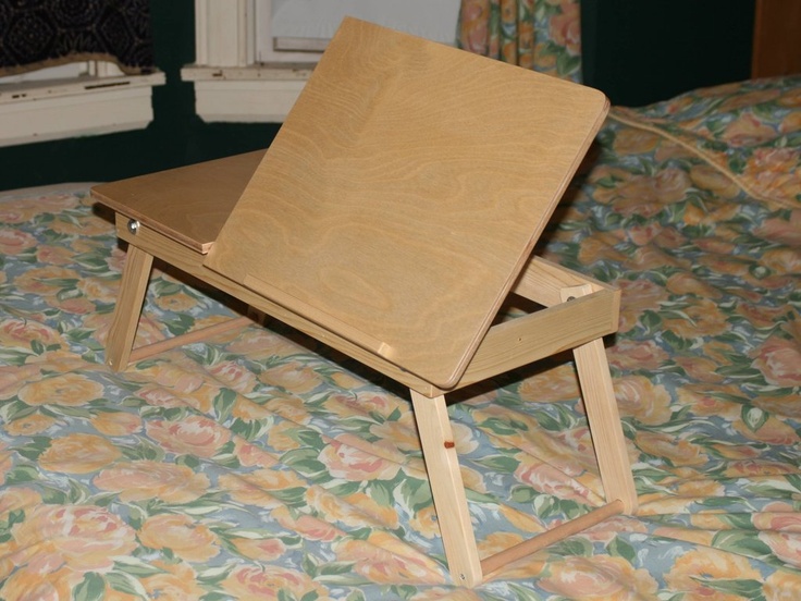 a small wooden table sitting on top of a floral bedspread in front of a window