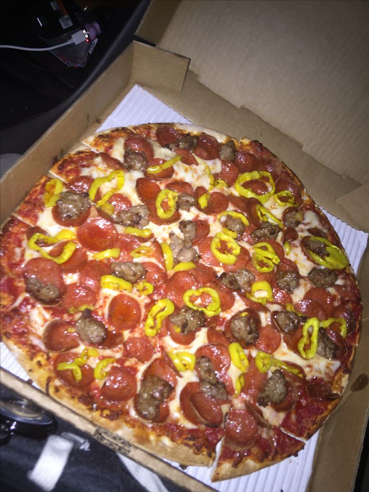 a pizza with pepperoni, sausage and peppers in a box