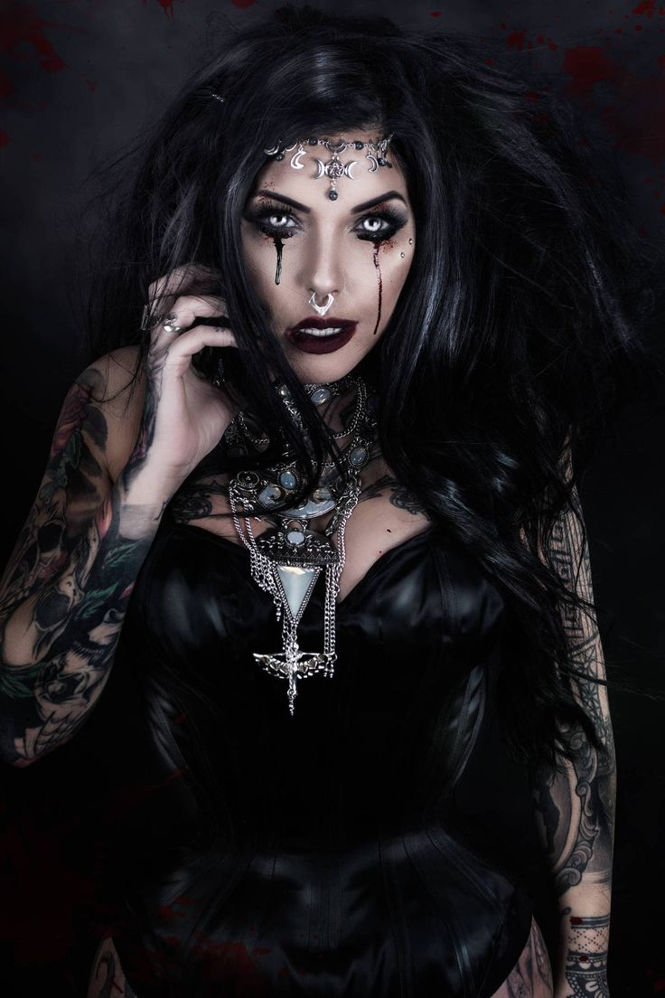 a woman with dark makeup and tattoos on her face