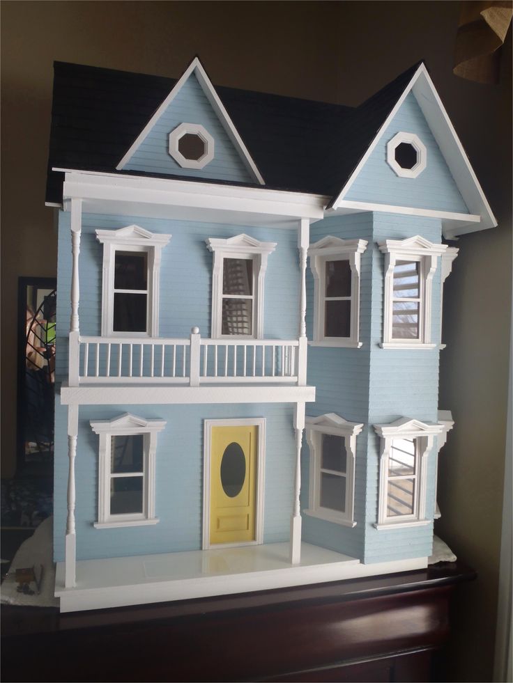 a blue doll house with white balconies and windows