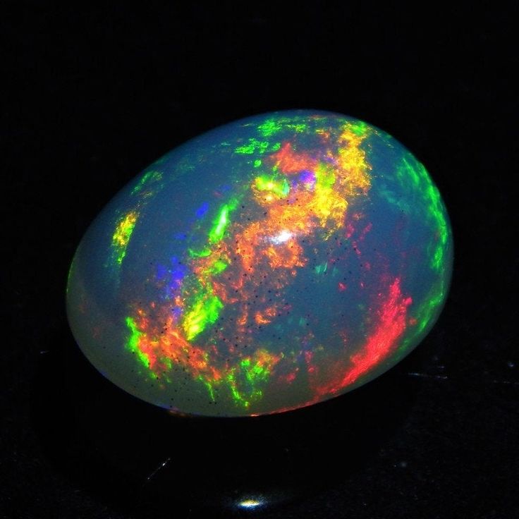 an opalite is shown in the dark with its bright green and orange colors