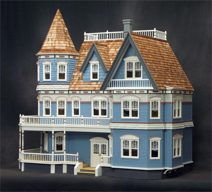 a blue doll house with white trim and brown roof on a black background in front of a dark backdrop