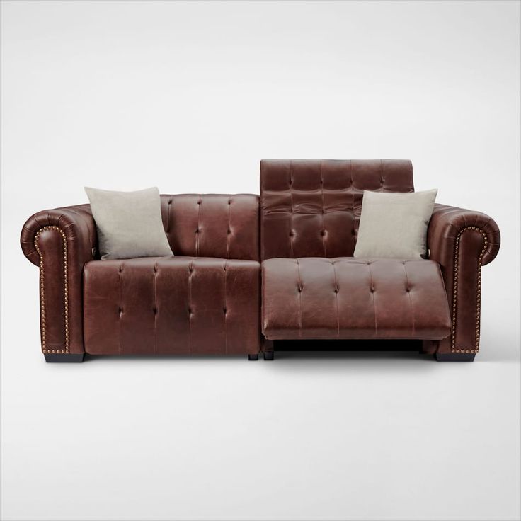 a brown leather couch with two pillows on it's back and one arm facing the camera