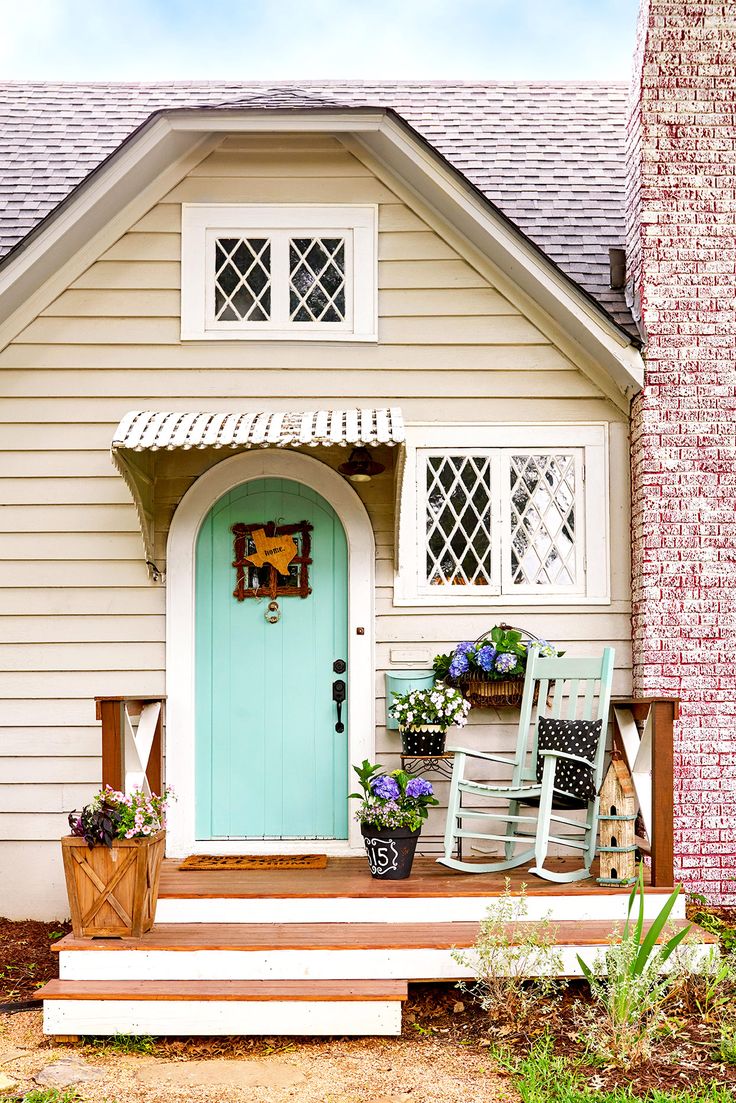 a blue door and two rocking chairs in front of a house