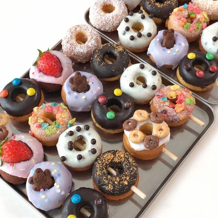 two trays filled with donuts covered in frosting and sprinkles